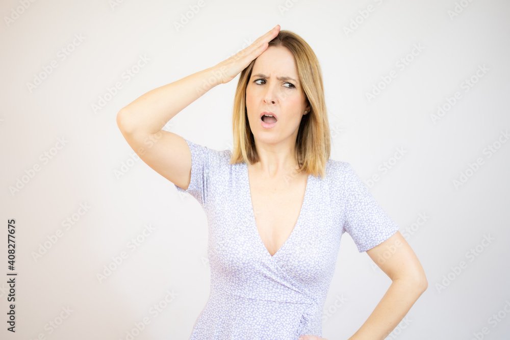 young blonde woman feeling horrified and shocked, raising hands to head and panicking at a mistake over green background. young blonde woman feeling horrified and shocked, raising hands to head and panicking at a mistake over green background.