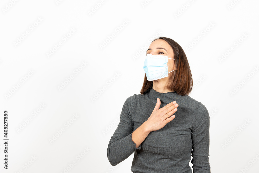 An hispanic woman greeting with her hand on the chest while wearing a medical face mask. Healthcare during Coronavirus pandemic concept. An hispanic woman greeting with her hand on the chest while wearing a medical face mask. Healthcare during Coronavirus pandemic concept.