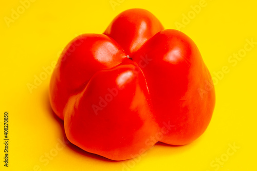 Upside-down vibrant red colorful pepper or paprika resembling a reflective pudding starkly contrasting with the yellow surface below. Studio low key food still life.
