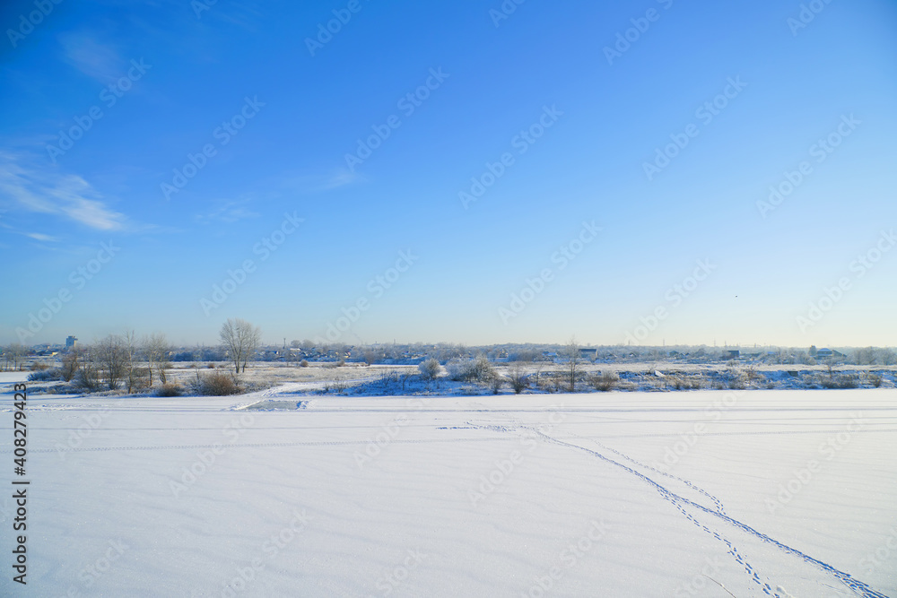 Winter landscape. Snow-covered lake in the distance is beautiful forest and beautiful fblue sky