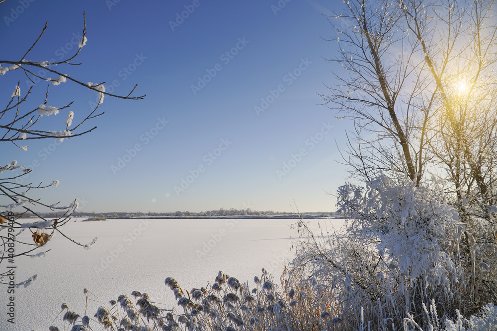 Snow-covered lake in the distance is the beautiful forest and beautiful fblue sky with sun