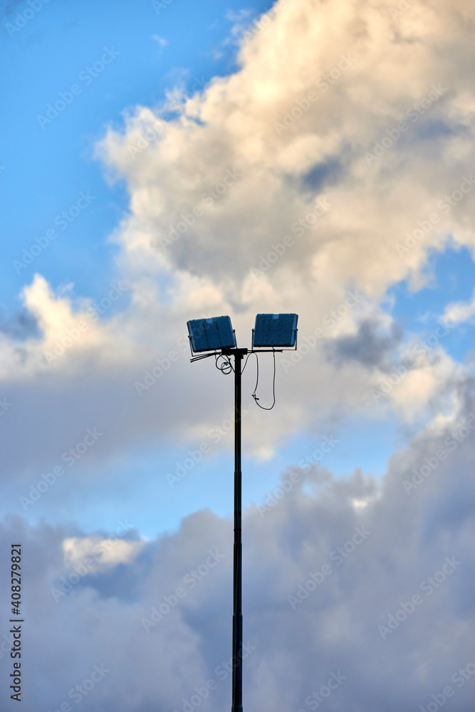 lighting pole of a stadium between clouds and blue sky lighting pole of a stadium between clouds and blue sky