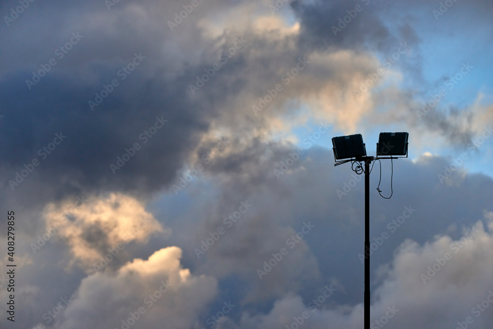 lighting pole of a stadium between clouds and blue sky lighting pole of a stadium between clouds and blue sky