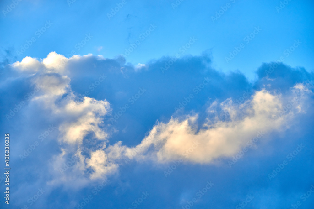 Wind-driven threatening cloud formations cover the blue sky and blend into various colors