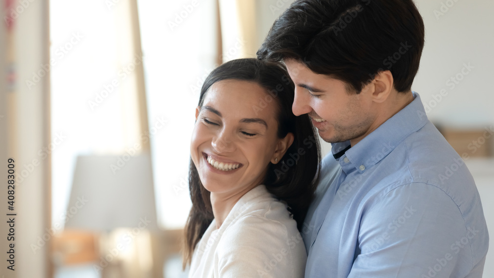 Close up smiling woman and man hugging, enjoying tender moment, standing at home, husband embracing wife from back, expressing love and care, young couple spending free time together, romantic date Close up smiling woman and man hugging, enjoying tender moment, standing at home, husband embracing wife from back, expressing love and care, young couple spending free time together, romantic date