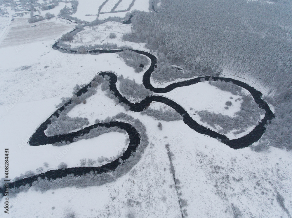 Beautiful winter nature. Aerial view of curved river. Snowy forest and field.