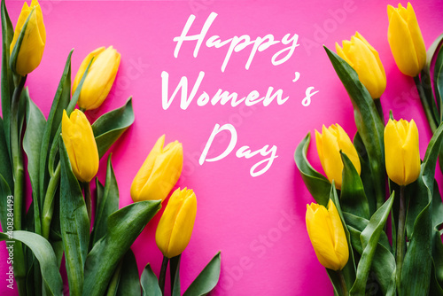 Yellow tulips on pink pastel background. Holiday greeting card for Women's Day. Top view, flat lay.