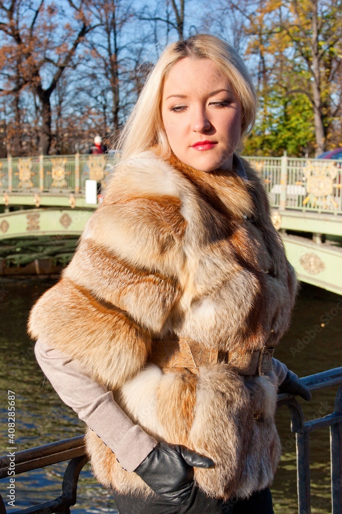 The girl in a fur coat walks around the city on a sunny day (poster mockup) The girl in a fur coat walks around the city on a sunny day (poster mockup)