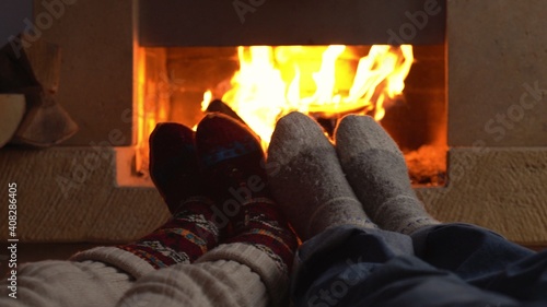 Couple in love wearing knitted woolen socks lying next to the fireplace