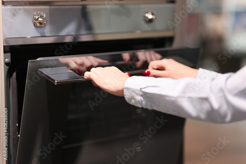 Woman opens oven. Choice of household appliances for the kitchen © megaflopp