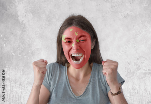 Young woman with painted flag of China and open mouth looking energetic with fists up photo