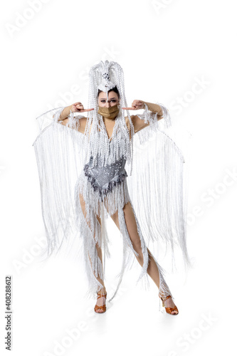 Pointing. Beautiful young woman in carnival, stylish masquerade costume with feathers and golden face mask on white background. Concept of holidays celebration, festive time, dance, party, fashion