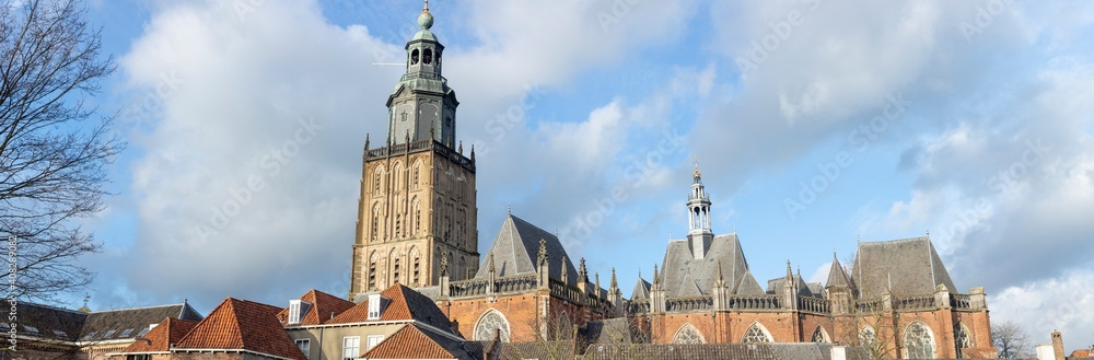 Church tower and rooftops part of cityscape skyline of medieval Hanseatic city Zutphen in The Netherlands against a sunny soft blue sky with clouds