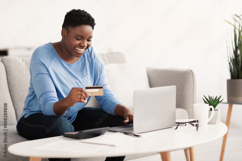 Black woman using computer and credit card at home Black woman using computer and credit card at home