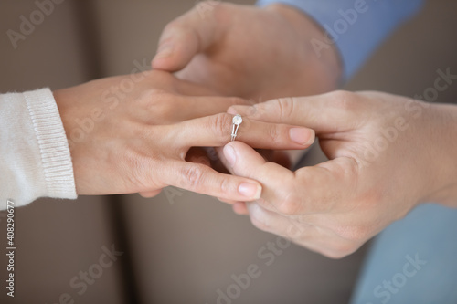 Close up affectionate man putting wedding ring on woman bride finger, loving boyfriend proposing marriage to girlfriend, engagement, proposal acceptance concept, young couple decided getting married © fizkes