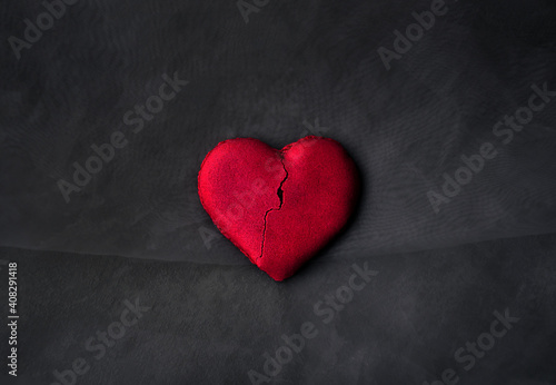 A semi-broken heart-shaped cookie. Dark background
