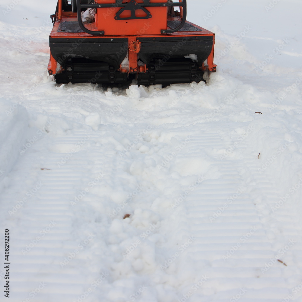 Old Russian utility snowmobile roller wheeled twin crawler drive gear with track on white snow close up Old Russian utility snowmobile roller wheeled twin crawler drive gear with track on white snow close up