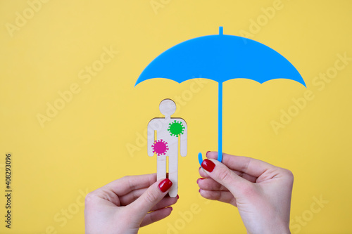 Female hand holds an umbrella and wooden man with bacteria stickers