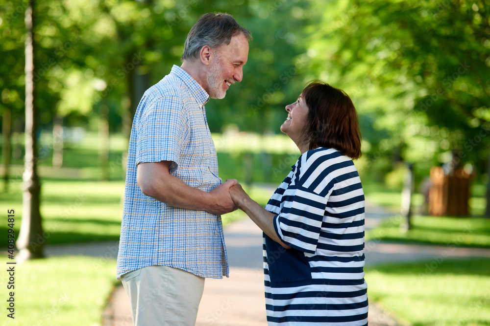 Smiling caucasian couple looking at each other. Green summer park. Smiling caucasian couple looking at each other. Green summer park.