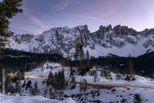 Car light trails along a road running through a magnificent snowy mountain landscape in the European Alps at dusk photo