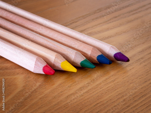 Five different coloured pencils on a wooden table