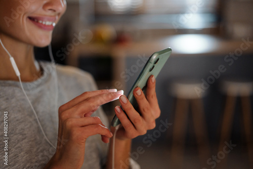 Smiling young woman listening music with earphones and mobile phone