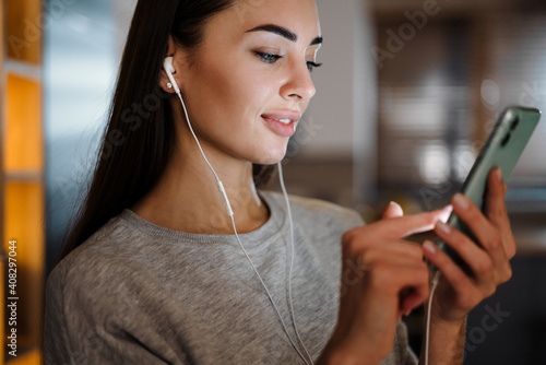 Focused young woman listening music with earphones and mobile phone