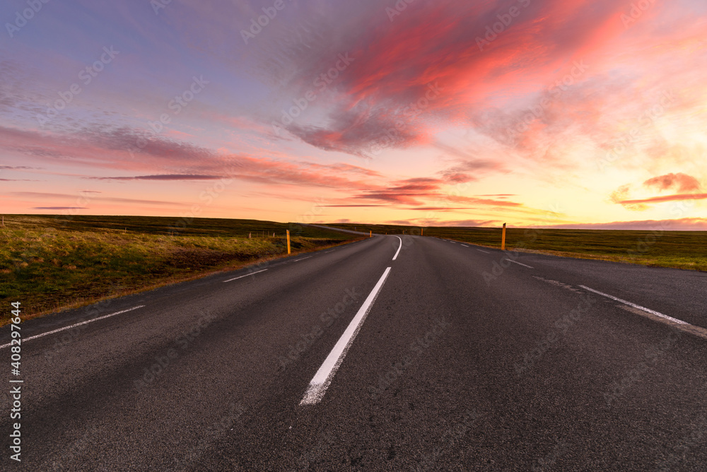 Stunning summer sunset over a deserted road through the countryside of Iceland