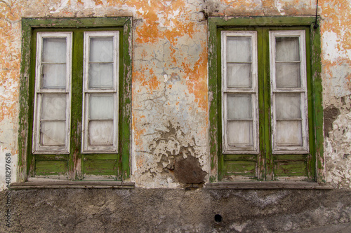 Old colorful green windows on a yellow wall