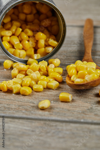 A can of boiled sweet corn on a wooden table with a spoon