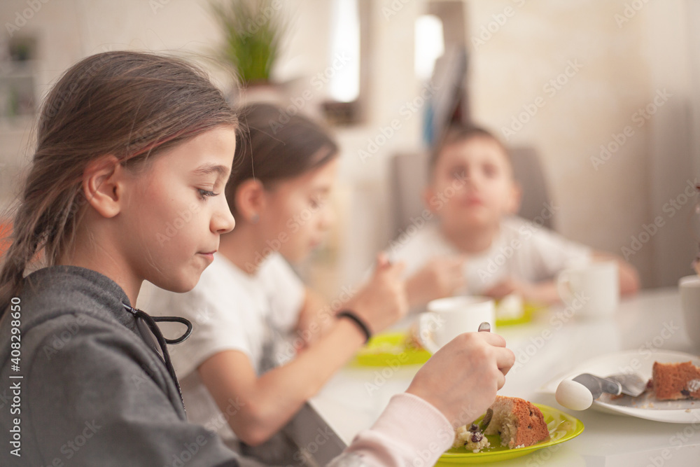 The group of kids eating the easter bread on spring holiday with tea