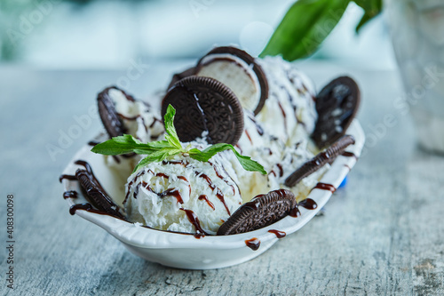 Oreo ice-cream with chocolate syrup and mint in the white plate on the marble background