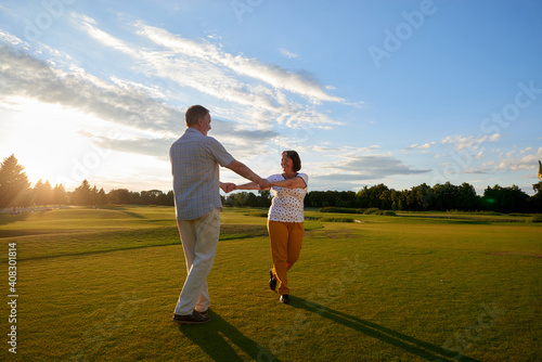 Happy mature couple holding hands on the field. Senior man and his wife having fun outdoors.