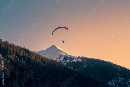 Paraglider over mountain peak in the alps. Paragliding in the alps.