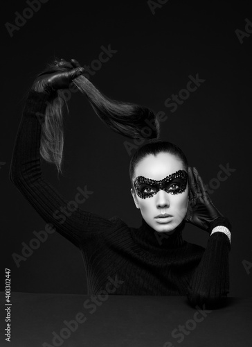 Elegant brunette woman in turtleneck sweater and sequins mask