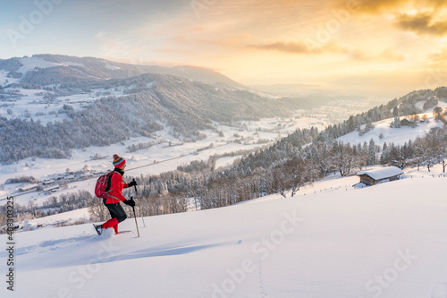 nice active senior woman snowshoeing in the Allgaeu Alps near Oberstaufen with view into the Bregenzerwald, Vorarlberg, 