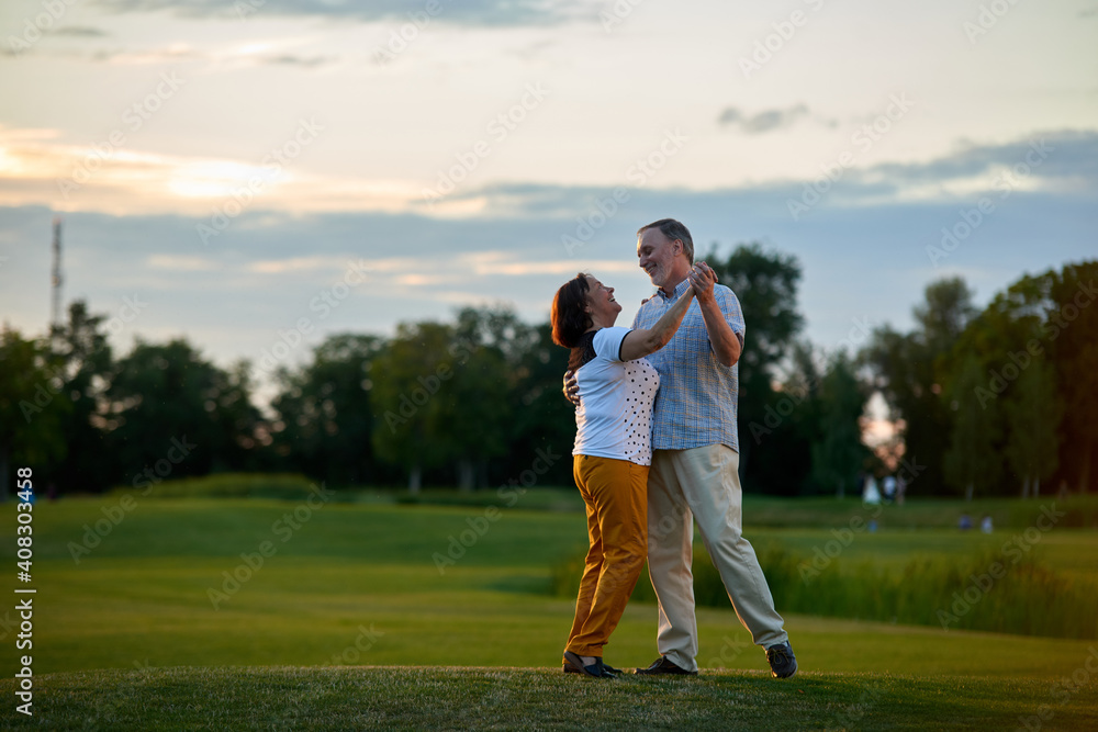 Happy couple dancing outdoors. Mature man and woman on the green field. Happy couple dancing outdoors. Mature man and woman on the green field.