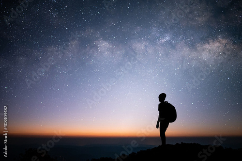 Silhouette of young traveler watched the star and milky way on top of the mountain alone in the morning before sunrise. He is happy to be with herself and stay with nature at twilight time.