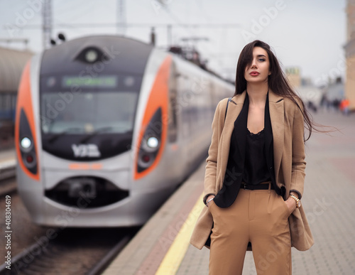 Woman model stands at train station in suit