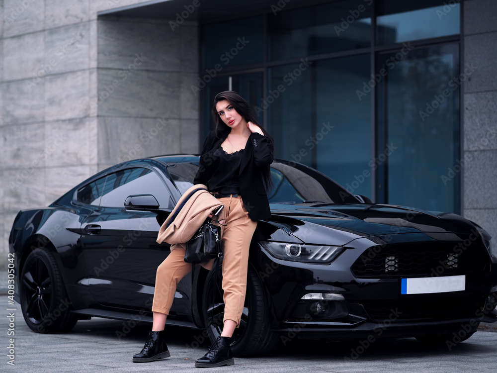 Woman stands near a sports car in the city
