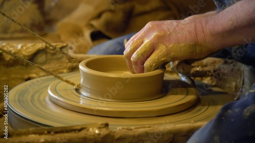 Close-up of the hands of a man who makes a clay jug on a Potter's wheel.