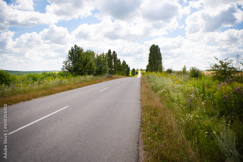 Asphalt flat road between rural fields. Summer, sunny day, beautiful sky.