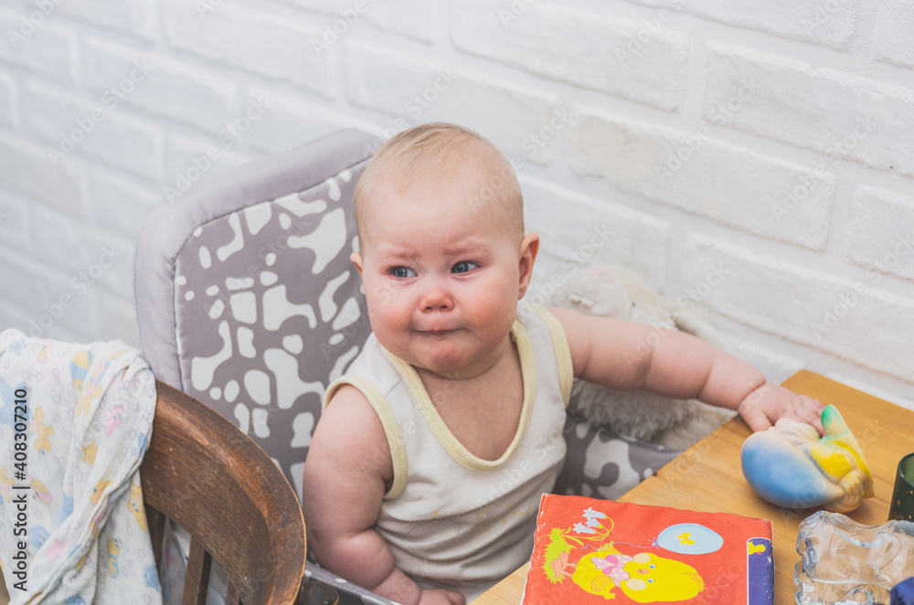 Disgruntled upset baby girl sitting at the dinner table Disgruntled upset baby girl sitting at the dinner table