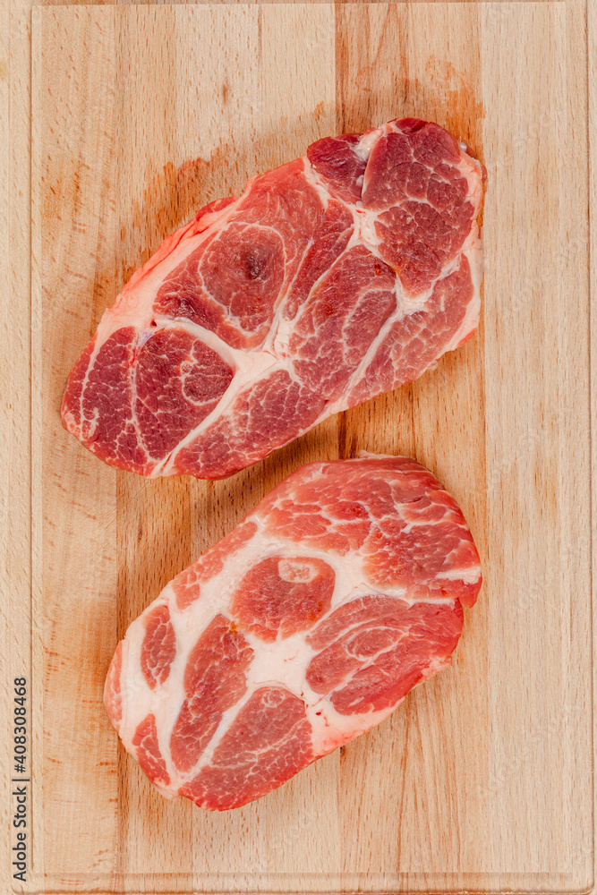 fresh raw marbled pork steak on a solid beech wood cutting board fresh raw marbled pork steak on a solid beech wood cutting board