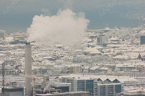 Aerial view of smoking chimney in snow covered Zurich city Switzerland after record high snowfall cloudy day
