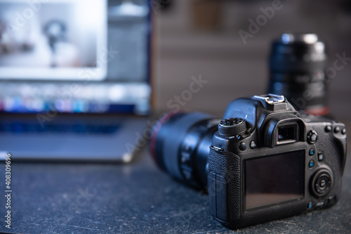 Canvas Print Digital professional camera on the table near the laptop close up