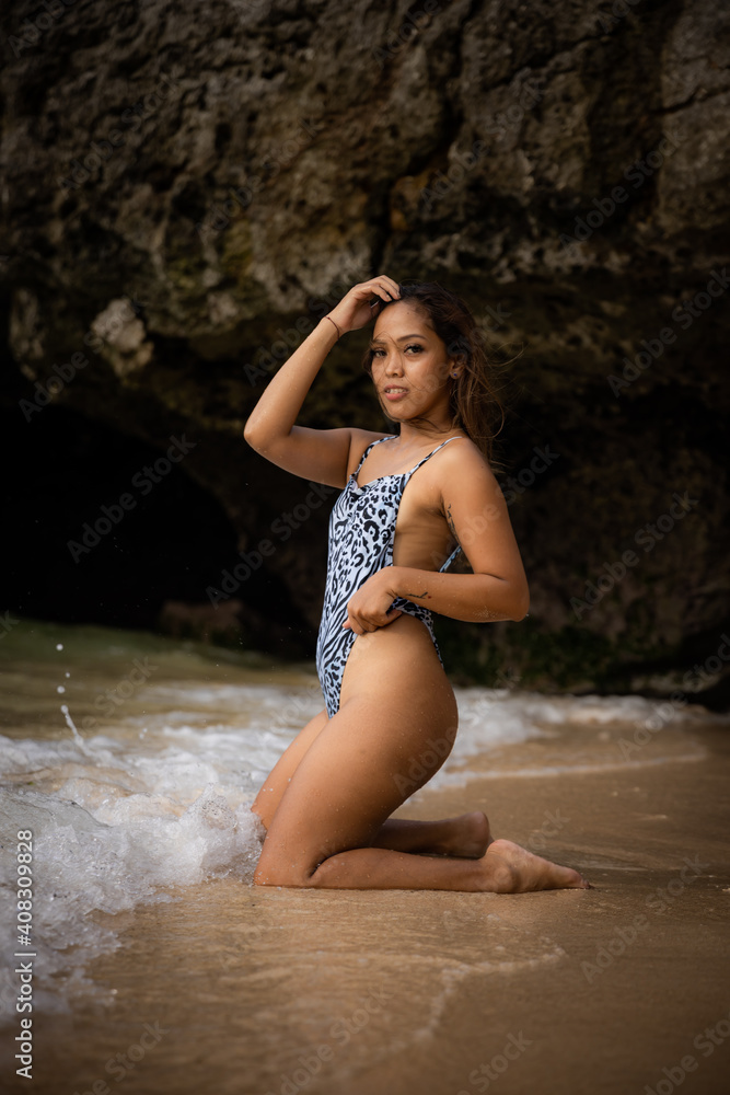 Stylish Asian woman posing by the sea. Spend time on the beach. Sexy body. Tanned skin. Tropical island travel concept. Summer vacation. Bali, Indonesia Stylish Asian woman posing by the sea. Spend time on the beach. Sexy body. Tanned skin. Tropical island travel concept. Summer vacation. Bali, Indonesia