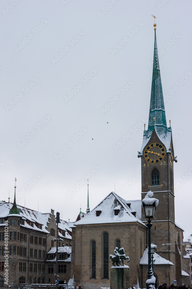 Snow covered old town Zurich with church bell tower winter time cloudy day