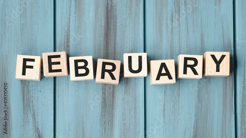 February text on wooden cubes on wooden background.