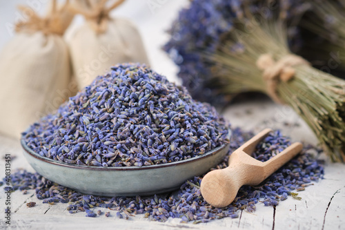 Blue plate of dried lavender. Wooden scoop of dry lavender flowers. Lavender bouquet and sachets on background.